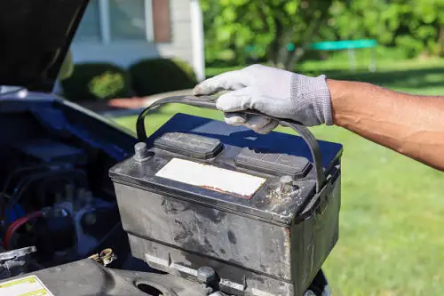 An African American man taking a car battery out of a truck